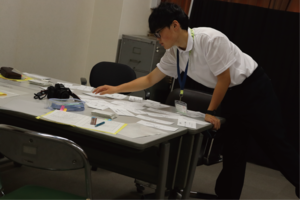 机の上で書類を手に取る生徒の画像