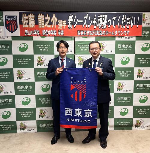 佐藤選手と市長が西東京と書かれたFC東京の垂れ幕を持っている写真