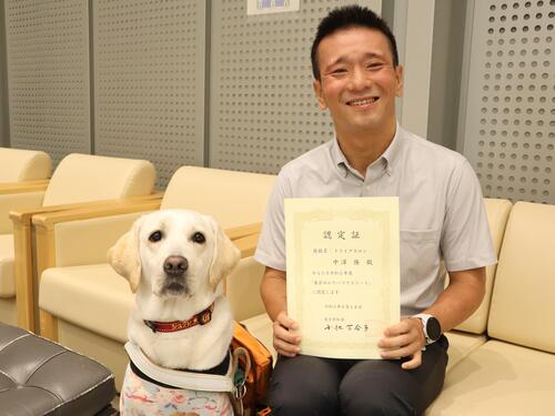 認定証を持つ中澤 隆さんと盲導犬シュクレ